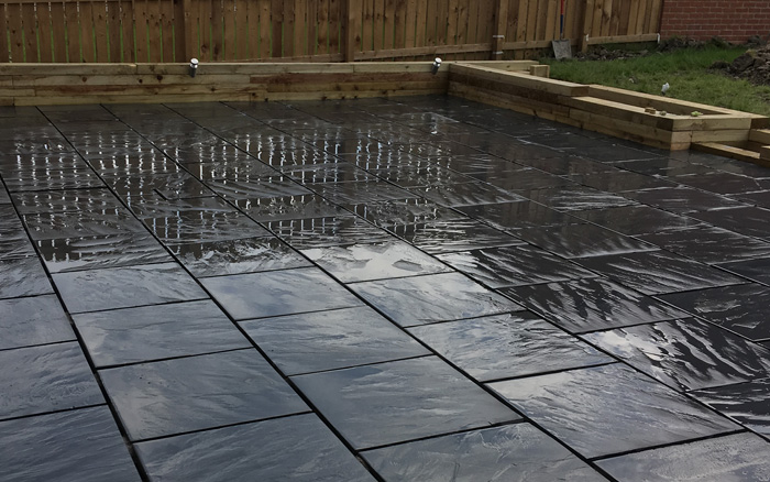 Photo of clean and wet black paving in garden